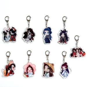 Puede incluir: Una colección de llaveros acrílicos de estilo anime con varios personajes. Cada llavero tiene un anillo y un cierre de metal plateado. Los personajes están representados en colores vibrantes, con detalles.