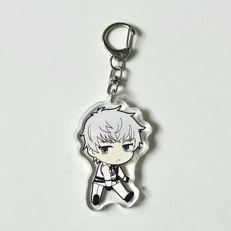 May include: A clear acrylic keychain featuring a cartoon character with white hair, wearing a white shirt and black pants. The character has blue eyes and a serious expression.