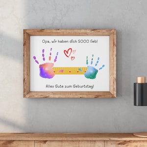 May include: A framed print with a wooden frame. The print features colorful handprints, hearts, and German text that reads "Opa, wir haben dich SOOO lieb!" and "Alles Gute zum Geburtstag!"