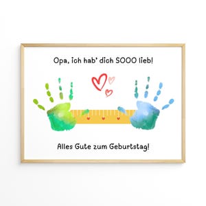 May include: A framed print with the text "Opa, ich hab' dich SOOO lieb!" and "Alles Gute zum Geburtstag!" features green and blue handprints, red hearts, and a yellow ruler design. The artwork is on a white background.