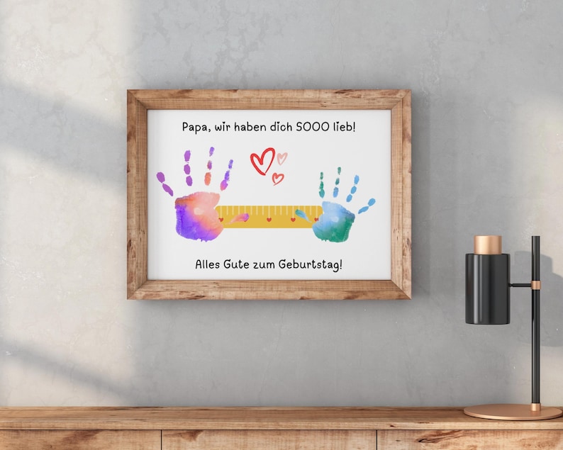 May include: A framed print with a wooden frame. The print features colorful handprints, hearts, and German text. The text reads "Papa, wir haben dich SOOO lieb!" and "Alles Gute zum Geburtstag!"