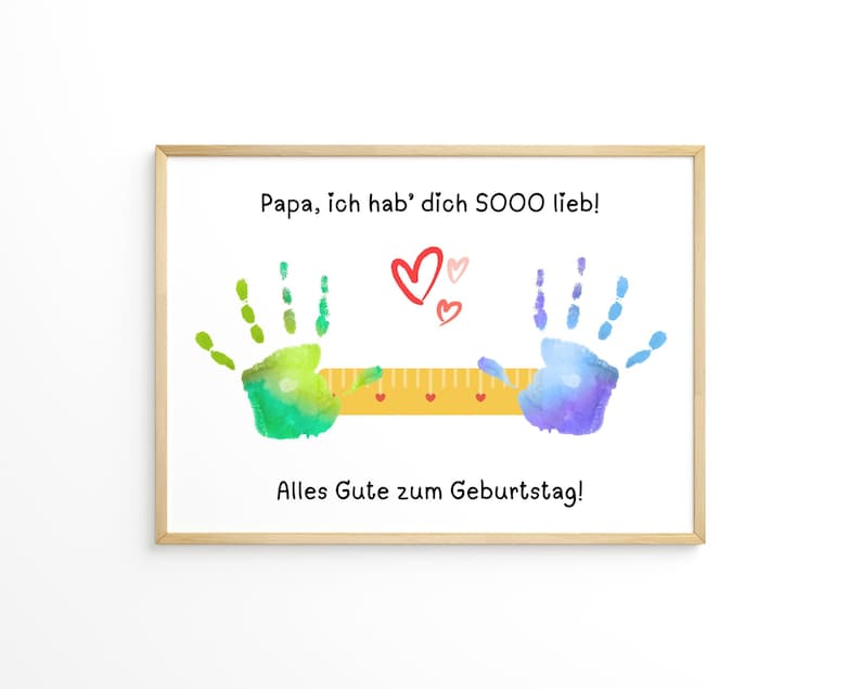 May include: A framed print with the text "Papa, ich hab' dich SOOO lieb!" and "Alles Gute zum Geburtstag!" features colorful handprints and hearts. A yellow ruler is between the handprints. The print is in a light wood frame.