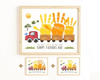 Puede incluir: Una impresión enmarcada con un tema del Día del Padre. La obra de arte presenta huellas de manos en amarillo y naranja, que se asemejan a vagones de tren, tirados por un camión rojo. El texto dice "You are LOADS of fun Dad! HAPPY FATHER'S DAY".