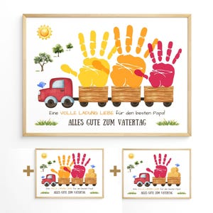 Pu&ograve; includere: Una stampa incorniciata con un design di treno con impronte di mani gialle, arancioni e rosse. Un camion rosso tira il treno, con testo in tedesco: "Eine VOLLE LADUNG LIEBE f&uuml;r den besten Papal ALLES GUTE ZUM VATERTAG".