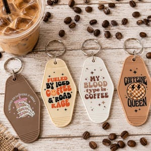 May include: Four retro-style keychains with coffee-themed designs and phrases. One brown keychain says "Running on Caffeine & Chaos." Other keychains say "Fueled by Iced Coffee & Road Rage," "My Blood Type is Coffee," and "Caffeine Queen."