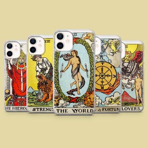 May include: A collection of five clear phone cases featuring tarot card designs. Each case displays a different card, including "The World," "Strength," and "The Lovers." The cards have colorful illustrations with detailed imagery and text.