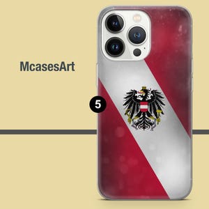 Peut inclure: Une coque de t&eacute;l&eacute;phone transparente avec un design de drapeau autrichien rouge, blanc et noir. Le drapeau pr&eacute;sente un blason avec un aigle noir et une bande blanche avec une bande rouge de chaque c&ocirc;t&eacute;. La coque a une d&eacute;coupe pour les objectifs de l'appareil photo du t&eacute;l&eacute;phone.