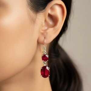 Puede incluir: Pendientes colgantes de plata con dos piedras preciosas rojas. La piedra superior es redonda, la inferior ovalada. Los pendientes cuelgan de un gancho de plata. Las piedras rojas añaden elegancia.