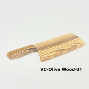 May include: A cleaver-shaped kitchen utensil crafted from olive wood, featuring a distinct natural grain pattern and a smooth finish. The handle includes a dark wood inlay detail. The text VC-Olive Wood-01 is printed in black below the object.