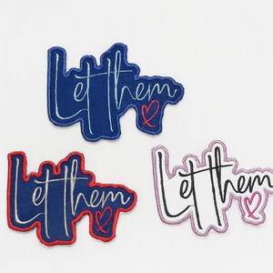 May include: Three embroidered patches with the phrase "Let them" in a cursive font. The patches are in blue, navy with red trim, and white with a pink outline. Each patch includes a small heart.