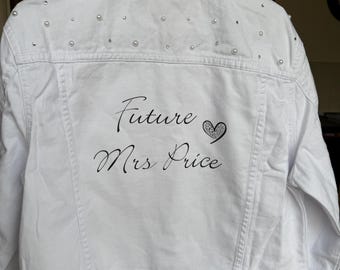 May include: White denim jacket embellished with pearls and rhinestones. The back of the jacket features the text "Future Mrs Price" in elegant script, with a heart design. A stylish bridal or wedding-themed garment.