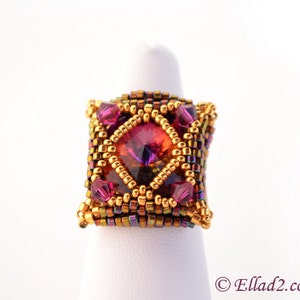 May include: A square-shaped ring with a large, faceted, iridescent purple and orange gemstone surrounded by gold and bronze seed beads.