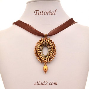 May include: A gold beaded pendant necklace with a brown ribbon. The pendant is a large oval shape with a smaller oval hole in the center. The pendant has a teardrop-shaped bead hanging from the bottom.