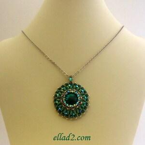 Op de afbeelding: Een zilveren ketting met een groene kralenhanger met een grote smaragdgroene edelsteen in het midden. De hanger is rond en heeft een symmetrisch ontwerp.