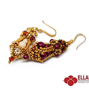 May include: A pair of gold and burgundy beaded earrings with a dangling crystal. The earrings are made with small beads and have a unique, intricate design.
