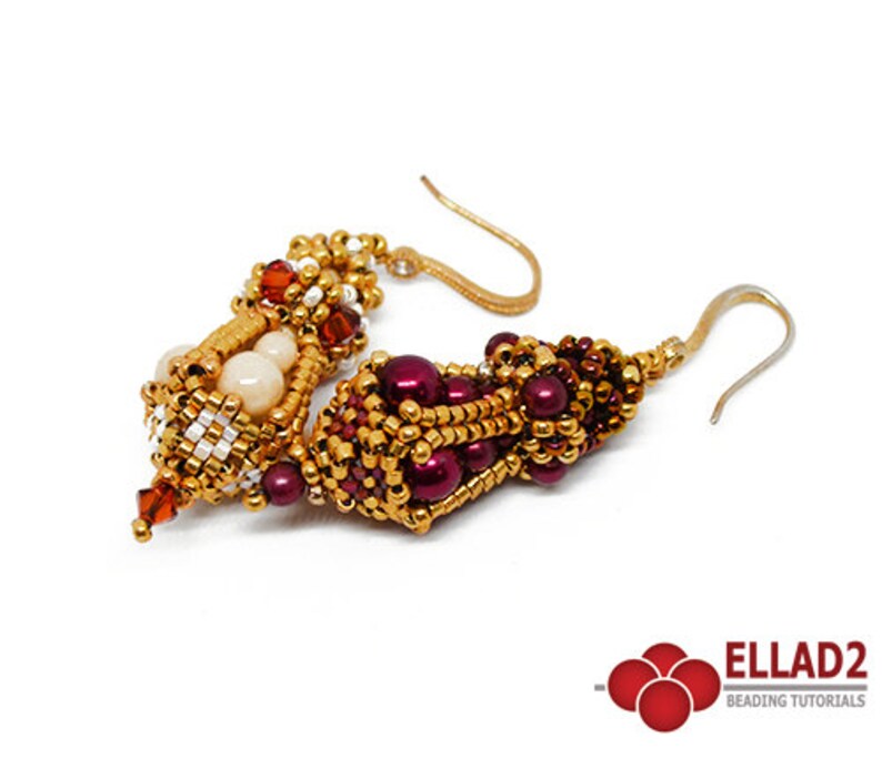 May include: A pair of gold and burgundy beaded earrings with a dangling crystal. The earrings are made with small beads and have a unique, intricate design.
