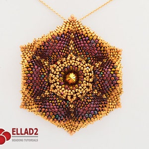 Puede incluir: Un colgante de cuentas doradas y burdeos con un centro de cristal, colgado de una cadena dorada. El colgante tiene forma de flor con múltiples capas de cuentas.