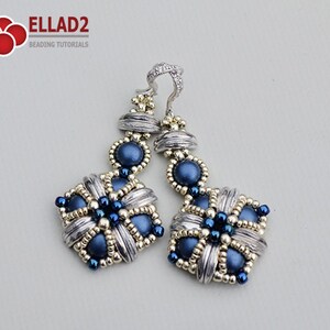 May include: A pair of handcrafted earrings featuring a silver-tone metal design with intricate detailing. The earrings incorporate dark blue beads and small gold-colored accents. The earrings have a square shape with a floral pattern and a decorative top.