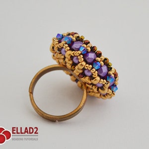 K&ouml;nnte beinhalten: Ein runder Ring aus lila und goldenen Perlen. Der Ring ist aus kleinen Perlen gefertigt und hat eine goldene Band.