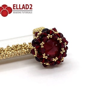 Może przedstawiać: Złoty pierścionek z czerwonym kamieniem szlachetnym otoczonym mniejszymi czerwonymi i złotymi koralikami. Pierścionek leży na białym tle.