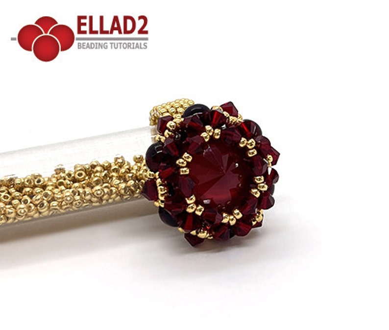 Może przedstawiać: Złoty pierścionek z czerwonym kamieniem szlachetnym otoczonym mniejszymi czerwonymi i złotymi koralikami. Pierścionek leży na białym tle.