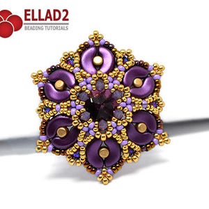 Może przedstawiać: Broszka w kształcie kwiatu wykonana z fioletowych i złotych koralików z dużym fioletowym kamieniem szlachetnym w środku. Broszka jest wykonana z koralików nasiennych i ma szczegółowy wzór.