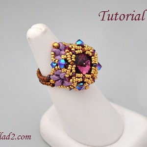 May include: A beaded ring with a large, faceted, magenta-coloured centre stone. The ring features gold, purple, and blue beads, with the word "Tutorial" in the upper right corner. The website ellad2.com is visible in the lower left corner.