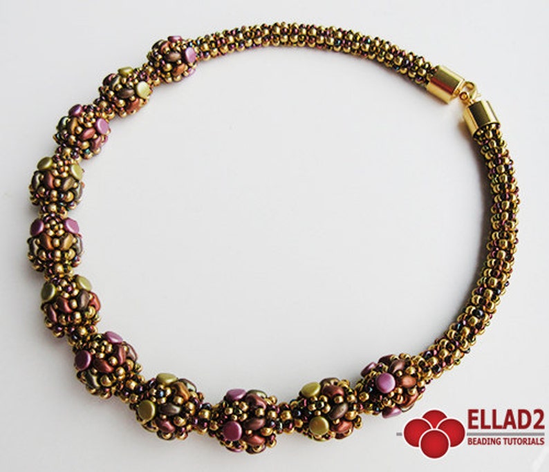May include: A gold beaded necklace with a clasp closure. The necklace features a series of large, multi-colored beads that are made of smaller beads. The beads are in shades of brown, gold, and purple.