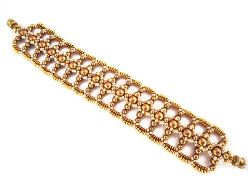 K&ouml;nnte beinhalten: Ein goldfarbenes Armband mit geometrischem Muster. Das Armband besteht aus kleinen goldenen Perlen und wei&szlig;en Perlen.