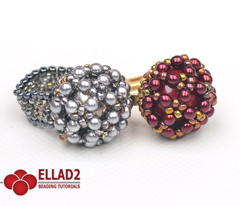 May include: Two beaded rings, one silver and one red with gold accents. The rings are made with small beads and have a round shape.