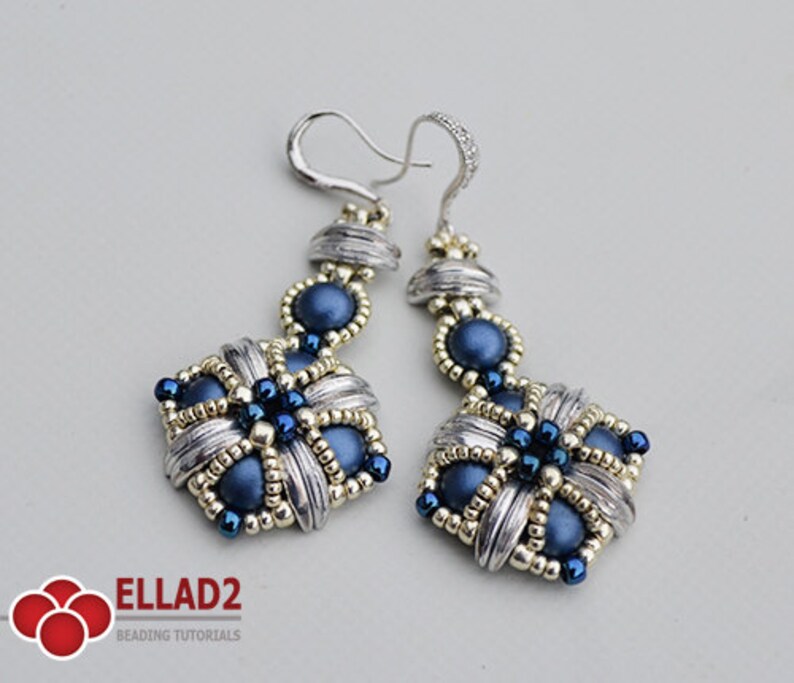 May include: A pair of handmade dangle earrings. The earrings feature a silver-colored metal design with woven details, accented with navy blue beads. The earrings have a hook closure and are designed with a floral pattern.