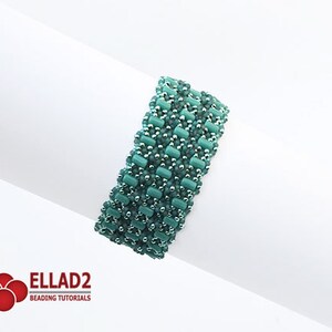 Op de afbeelding: Een turquoise en zilveren kralenarmband met een geometrisch patroon. De armband is gemaakt met kleine, vierkante kralen en is ongeveer 5 cm breed.