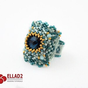 May include: A square-shaped ring with a blue gemstone surrounded by gold beads and a blue and green beaded design.