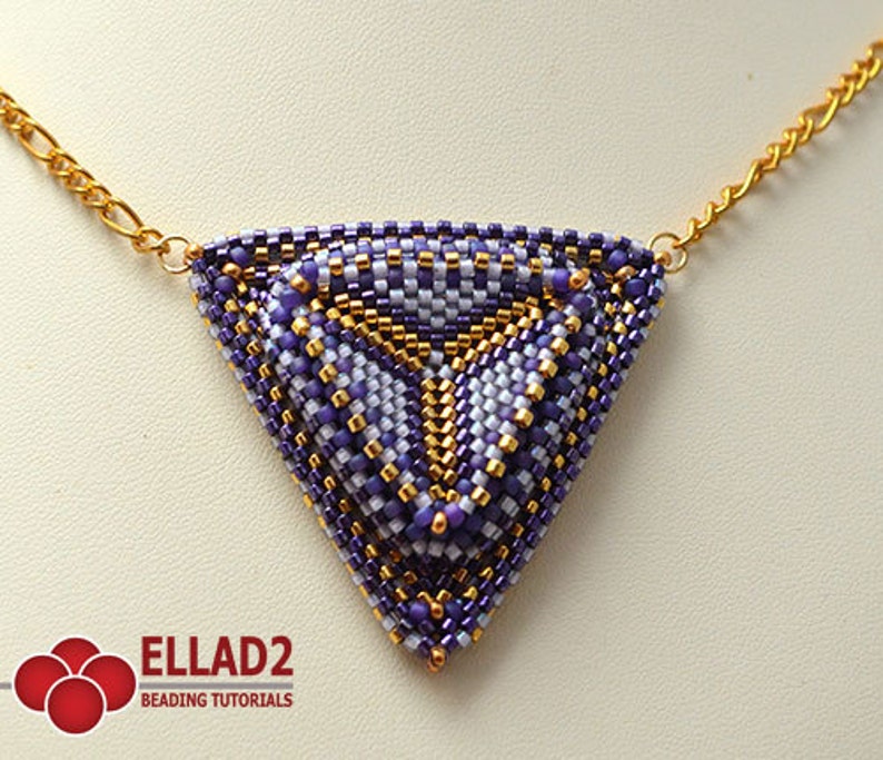 May include: A triangular beaded pendant necklace with a geometric pattern in shades of purple, white, and gold. The pendant is attached to a gold chain.