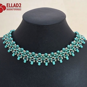 Op de afbeelding: Een turquoise en zilveren kralenketting met een delicaat, ingewikkeld ontwerp. De ketting is gemaakt van kleine, ronde kralen en heeft een cascade-effect.