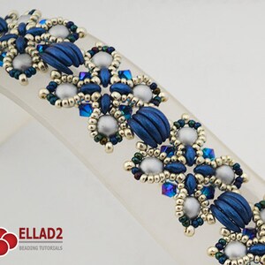 Op de afbeelding: Een kralenarmband met een blauwe, zilveren en gouden kleurstelling. De armband heeft een herhalend patroon van bloemvormige vormen.