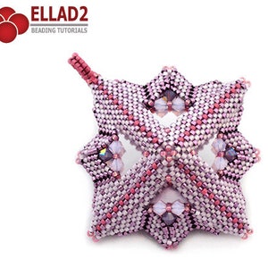 Pode incluir: Um ornamento em forma de estrela rosa e branco com um la&ccedil;o para pendurar. O ornamento &eacute; feito com pequenas contas de sementes e apresenta um design geom&eacute;trico.