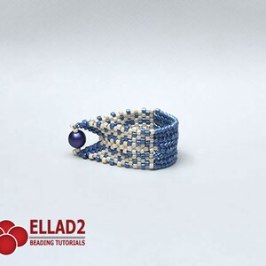 Peut inclure: Un bracelet en perles bleu et blanc avec un motif tiss&eacute;. Une perle bleu fonc&eacute; est suspendue au bord du bracelet. Le bracelet est pr&eacute;sent&eacute; sur un fond blanc. Le logo "ELLAD2 BEADING TUTORIALS" est visible en bas &agrave; gauche.