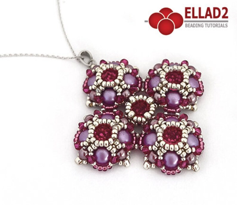 Pu&ograve; includere: Una collana con catena d'argento con un ciondolo fatto di sei fiori di perline viola e argento. I fiori sono disposti a forma di croce.
