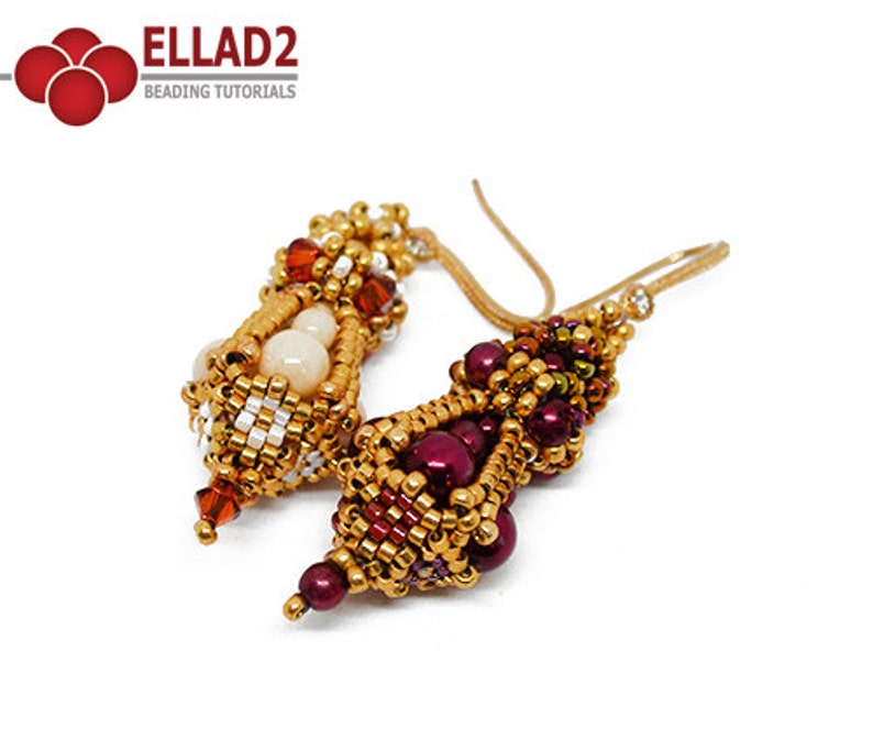 May include: A pair of gold beaded earrings with a burgundy and orange color scheme. The earrings are made with small beads and have a unique, intricate design.
