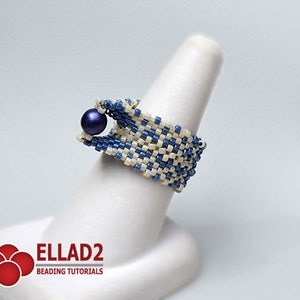 Peut inclure: Bague perl&eacute;e bleue et blanc cass&eacute;, orn&eacute;e d'une perle bleu fonc&eacute;. La bague est pr&eacute;sent&eacute;e sur un support blanc en forme de doigt. La bague est faite de petites perles carr&eacute;es tiss&eacute;es ensemble selon un motif g&eacute;om&eacute;trique. Le logo "ELLAD2 BEADING TUTORIALS" est en bas &agrave; gauche.