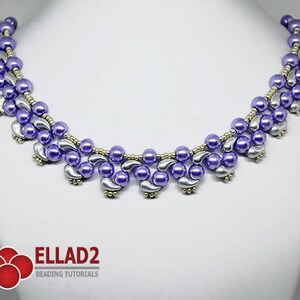 May include: A beaded necklace featuring lavender and silver beads. The necklace has a curved design with a series of lavender beads and silver teardrop-shaped accents. The necklace is displayed on a white background.
