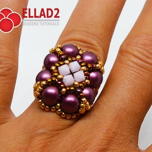 K&ouml;nnte beinhalten: Ein lila-goldener Perlenring mit einem quadratischen Design in der Mitte. Der Ring ist aus kleinen Perlen gefertigt und hat ein wei&szlig;es Quadrat in der Mitte.