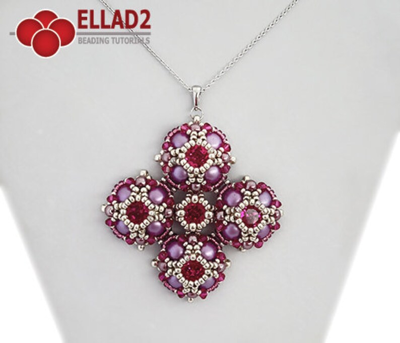 Pu&ograve; includere: Una collana con catena d'argento con un ciondolo fatto di perline rosa e argentate. Il ciondolo &egrave; un gruppo di sei gruppi di perline a forma quadrata, ciascuna con una perlina rosa centrale.