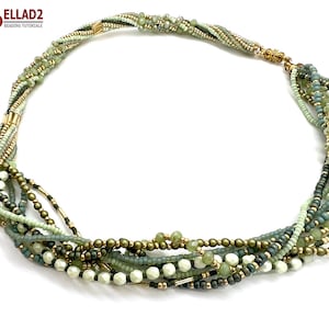 Op de afbeelding: Een meerrijige ketting gemaakt met groene en gouden kralen. De ketting is gemaakt met verschillende maten en vormen kralen, wat een uniek en opvallend ontwerp creëert.