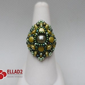 May include: A green and gold beaded ring with a pearl in the center. The ring is on a white display stand.