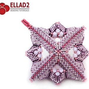 Pode incluir: Um ornamento em forma de estrela rosa e roxo com um design floral. O ornamento &eacute; feito com pequenas contas de sementes e tem um la&ccedil;o na parte superior para pendurar.