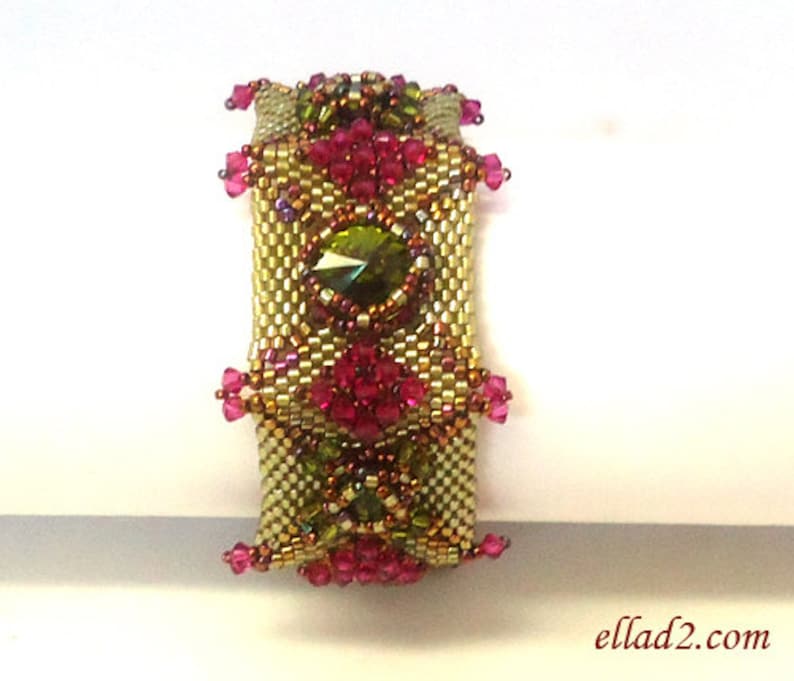 May include: A gold and green beaded bracelet with pink and purple accents. The bracelet features a large green gemstone in the center.