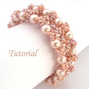 Puede incluir: Un brazalete delicado hecho con cuentas rosadas y doradas. El brazalete está hecho con una combinación de pequeñas cuentas de semillas y perlas más grandes. El brazalete es una pieza de joyería hermosa y elegante.