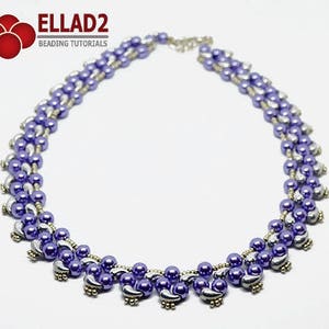 May include: A beaded necklace featuring a combination of purple and silver beads. The necklace has a layered design with a delicate chain clasp. The beads are arranged in a symmetrical pattern, creating a stylish accessory. The necklace is suitable for various occasions.